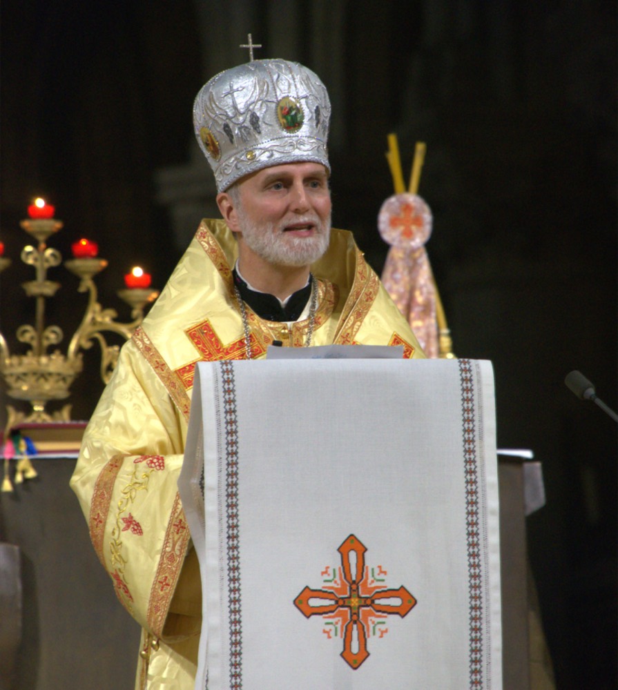 Archbishop Borys Gudziak in golden vestments, speaking at an altar.