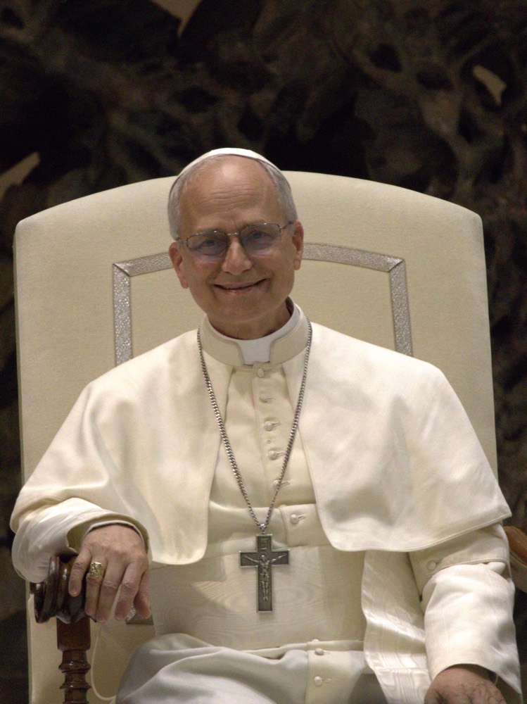 Pope Leo XIV seated, in white papal vesture.